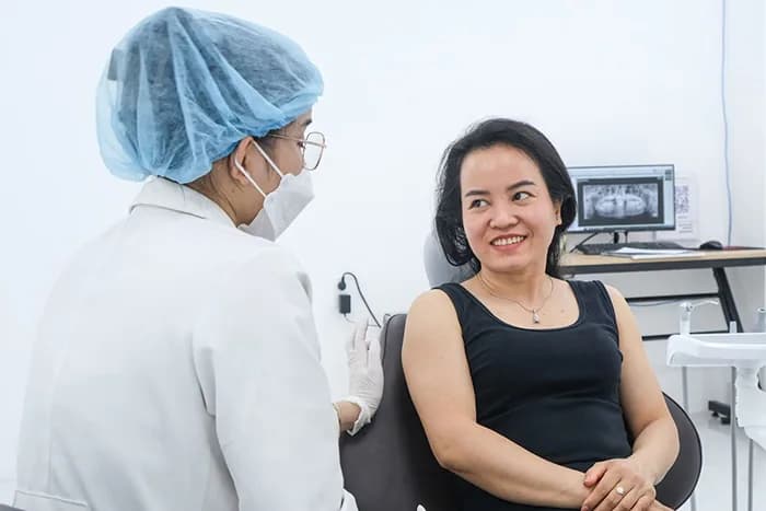 Bác sĩ tư vấn cho khách hàng trước khi điều trị, phim X-quang hiển thị trên màn hình